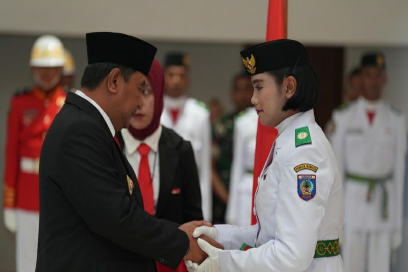 Penjabat Gubernur Sulbar Bahtiar Baharuddin (kiri) saat mengukuhkan anggota Paskibraka yang akan mengibarkan Sang Saka Merah Putih pada HUT ke-79 Kemerdekaan Republik Indonesia. ANTARA/HO/Diskominfo Sulbar.