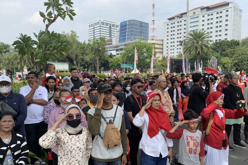 Warga di seberang Istana Merdeka Jakarta memberikan penghormatan saat bendera merah putih dinaikkan dalam Upacara Peringatan Detik-Detik Proklamasi yang digelar secara hibrida di Ibu Kota Nusantara dan Jakarta.ANTARA/Mario Sofia Nasution