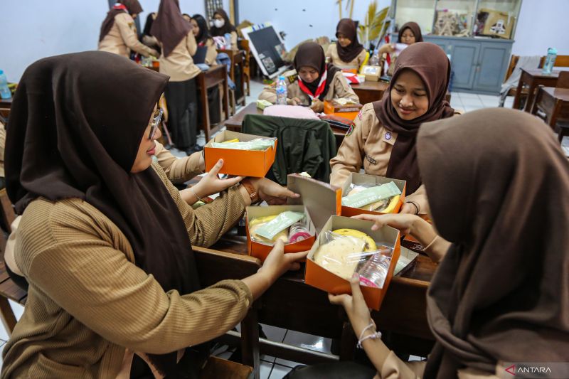 Sejumlah siswa membuka kemasan nasi kotak gratis saat mengikuti sosialisasi dan simulasi program makan siang gratis di SMA Negeri 3 Semarang, Jawa Tengah, Jumat (26/7/2024). ANTARA FOTO/Makna Zaezar