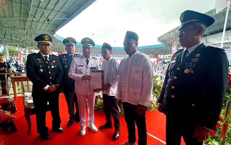Pj Bupati Barito Utara, Drs Muhlis didampingi Kepala Lembaga Pemasyarakatan Kelas II B Muara Teweh, Huzaifah Makmur Hidayah menyerahkan remisi umum kepada dua perwakilan warga binaan Lapas Kelas II B Muara Teweh, usai peringatan HUT ke-79 RI di arena Tiara Batara Muara Teweh, Sabtu, 17 Agustus 2024. (Foto: Dhani)