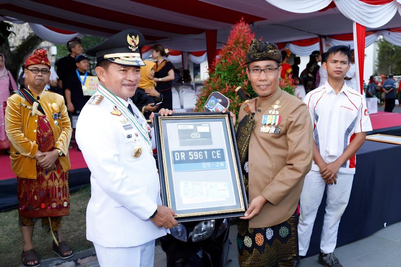 Kepala SMKN 3 Mataram Sulman Haris (kanan) menyerahkan dokumen kendaraan bermotor hasil konversi dan bahan bakar fosil menjadi listrik kepada Penjabat Gubernur NTB Hassanudin (kanan) di Mataram, Sabtu (17/8/2024). (ANTARA/HO-SMKN 3 Mataram)