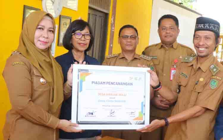 Kepala BPS Provinsi kalteng Agnes Widiastuti bersama Pj Bupati pulang pisau saat menyerahkan piagam kepada Kepala Desa Hanjak Maju. (FOTO: RETHA)