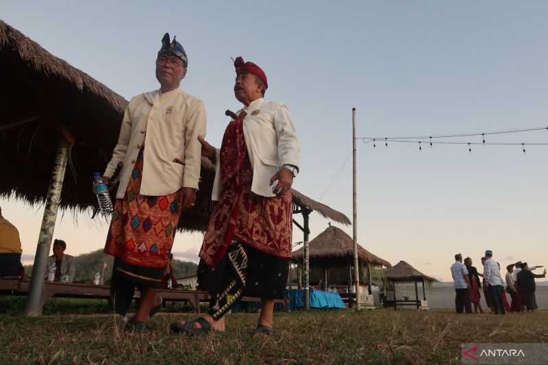 Dua pria mengenakan pakaian adat berjalan dekat bale sesaat jelang ritual bisoq keris di Desa Kebon Ayu, Kabupaten Lombok Barat, Nusa Tenggara Barat, Senin (15/7/2024). (ANTARA/Sugiharto Purnama)