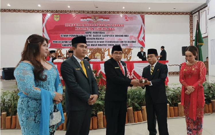 Ketua DPRD Gunung Mas periode 2019-2024 Akerman Sahidar menyerahkan palu sidang kepada Ketua Sementara DPRD Gumas Herbert Y Asin, Senin, 19 Agustus 2024. (FOTO: RISKA YULYANA)
