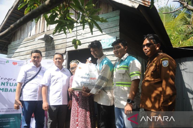 Perwakilan PT Sarana Daya Mandiri Happy Danni (kedua kanan) menyerahkan paket bantuan kebutuhan pokok kepada Nenek Khadijah (80), warga Desa Aluh-Aluh Besar, Kecamatan Aluh-Aluh, Kabupaten Banjar, Kalimantan Selatan, Selasa (20/8/2024). ANTARA/Abdul Hakim