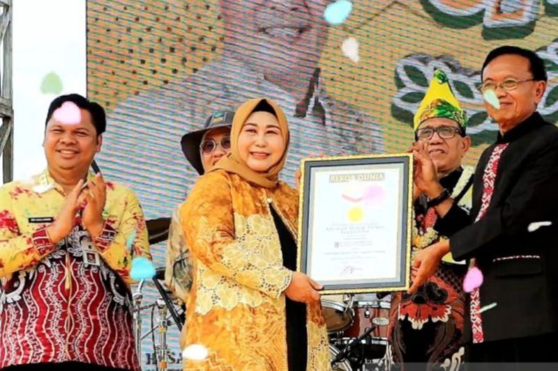 Ketua Dewan Kerajinan Daerah (Dekranasda) Raudatul Jannah atau Acil Odah (tengah) didamping Sekretaris Daerah Provinsi Kalsel Roy Rizali Anwar (kiri) menerima piagam penghargaan Direktur Operasional MURI Yusuf Ngadri terkait membentangkan kain Sasirangan terpanjang se-dunia di kawasan Perkantoran Provinsi Kalsel, Banjarbaru, Selasa (20/8/2024). ANTARA/HO-Biro Adpim Kalsel
