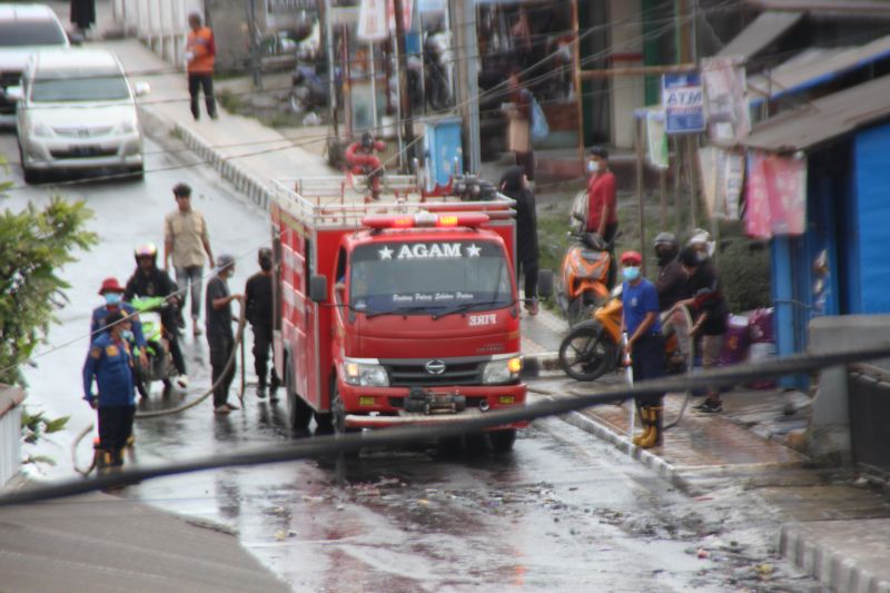 Petugas pemadam kebakaran menyiram jalan di Kabupaten Agam yang dipenuhi kabut abu vulkanik akibat terjadinya erupsi Gunung Marapi, Sabtu (24/8/2014). (ANTARA/Al Fatah)