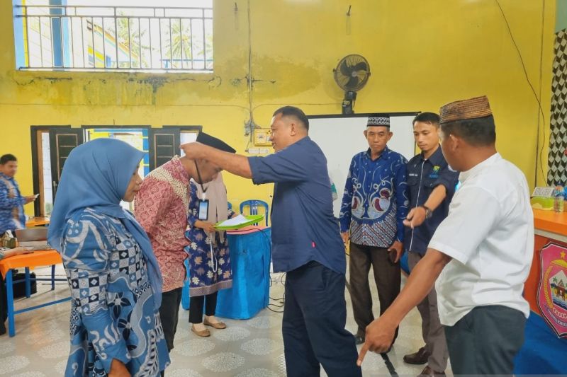 Kepala Bidang Komunikasi Dinas Kominfo Bone Bolango Muhammad Taufik Asnawi (tengah) menyematkan tanda peserta pada kegiatan peningkatan kemampuan Kelompok Informasi Masyarakat Desa Monano, Kecamatan Bone, Kabupaten Bone Bolango, Gorontalo. ANTARA/HO-Diskominfo Bone Bolango