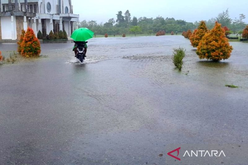 Ilustrasi - Pengendara sepeda motor melintasi jalan yang digenangi luapan air hujan dengan menggunakan payung di Kabupaten Yahukimo, Papua, Jumat (2/8/2024). ANTARA/HO-BPBD Yahukimo.
