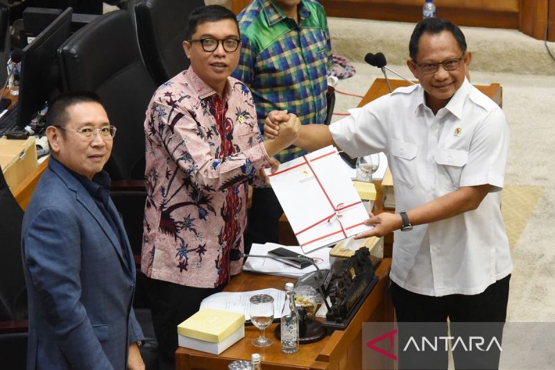 Menteri Dalam Negeri Tito Karnavian (kanan) menyerahkan berkas pandangan pemerintah kepada Wakil Ketua Badan Legislasi DPR yang juga pimpinan rapat Achmad Baidowi (tengah) dan disaksikan Ketua Badan Legislasi DPR Wihadi Wiyanto (kiri) dalam rapat pengambilan keputusan pembahasan RUU Pilkada antara Baleg DPR dengan Pemerintah di Kompleks Parlemen, Senayan, Jakarta, Rabu (21/8/2024). Badan Legislasi DPR mengesahkan Revisi Undang - Undang (RUU) Pilkada dibawa ke rapat Paripurna untuk disahkan menja