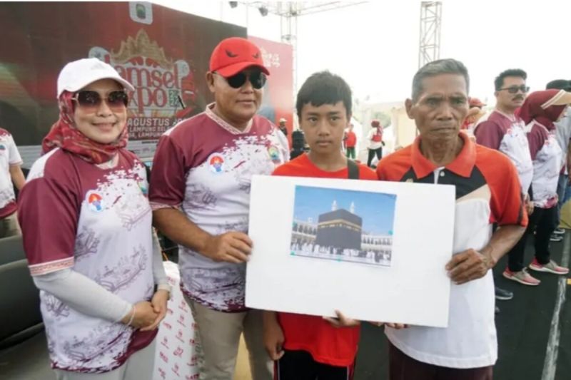 Salah seorang penerimah hadiah umrah gratis dari pemkab Lampung Selatan Devan Septa Saputra berfoto dengan bupati Lampung Selatan Nanang Ermanto. (ANTARA/HO/Kominfo Lampung Selatan)