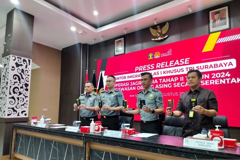 Petugas Imigrasi Kelas I Khusus TPI Surabaya menunjukkan paspor milik WNA yang diduga melanggar izin tinggal (ANTARA/Indra Setiawan)