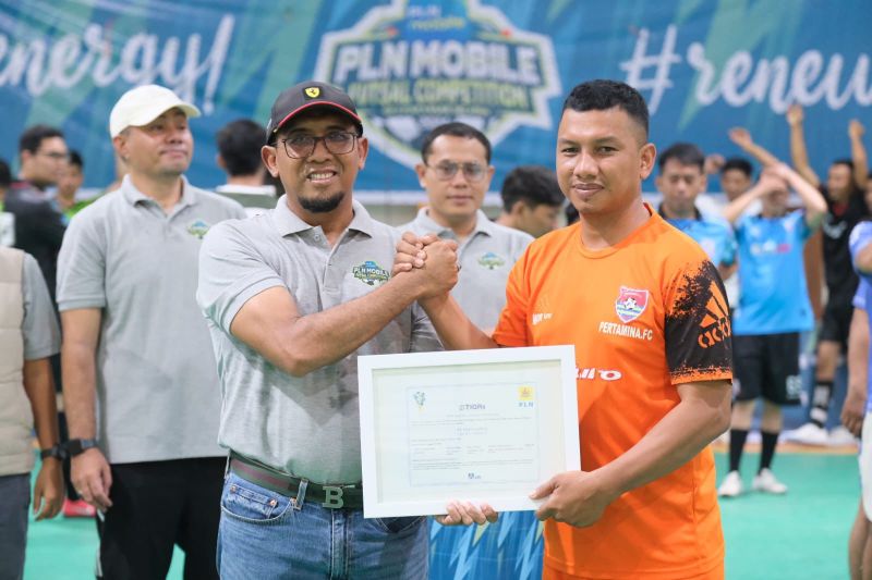 GM PLN UID Sulselrabar Budiono (kiri) saat memberikan secara simbolis Renewable Energy Certificate kepada salah satu perwakilan tim futsal Pertamina FC dalam PLN Mobile Futsal Competition 2024. ANTARA/HO-Humas PLN