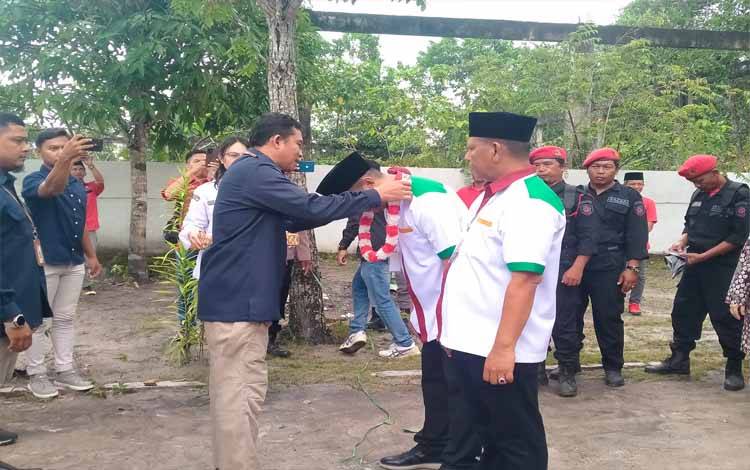 Ketua KPU Sukamara memasangkan kalung bunga kepada pasangan calon bupati dan wakil bupati Sukamara H. Masduki - Nur Effendi. (FOTO:NORHASANAH)