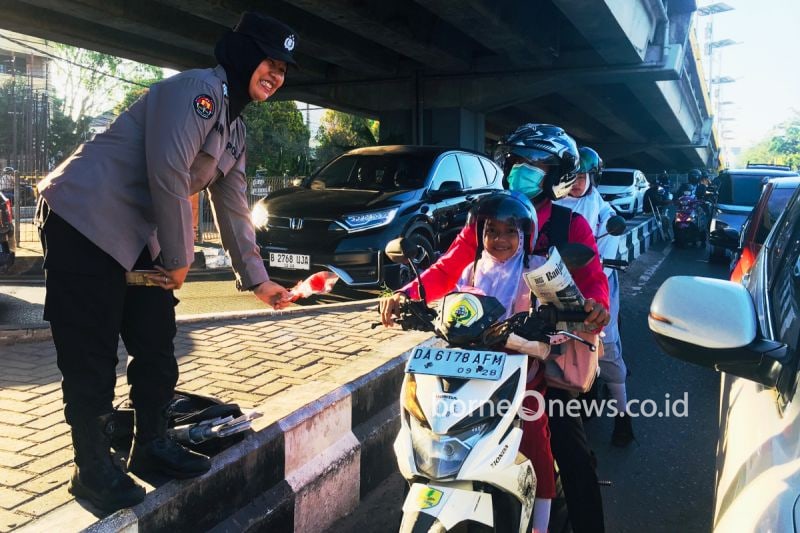 Polwan Polresta Banjarmasin membagikan bunga kepada pengguna jalan yang diselipkan kertas imbauan peduli kamtibmas menjelang Pilkada 2024, di Kota Banjarmasin, Senin (2/9/2024). ANTARA/HO-Humas Polresta Banjarmasi)