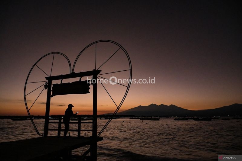 Siluet wisatawan memotret Gunung Rinjani saat matahari terbit di pantai Gili Trawangan, Desa Gili Indah, Tanjung, Lombok Utara, NTB, Sabtu (17/8/2024). Gili Trawangan merupakan satu dari tiga pulau kawasan wisata Gili Tramena (Gili Trawangan, Gili Meno, Gili Air) yang menjadi destinasi favorit wisatawan domestik dan mancanegara, dimana pada masa puncak liburan pada bulan Agustus okupansi hotel mencapai 90 persen.(ANTARA FOTO/AHMAD SUBAIDI)