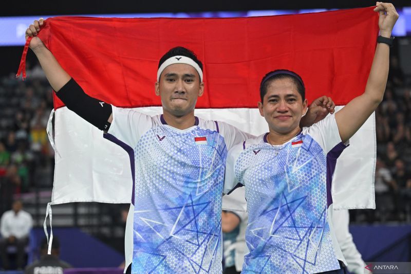 Pebulu tangkis ganda campuran Indonesia Leani Ratri Oktila (kiri) bersama rekannya, Hikmat Ramdani (kanan) mengangkat bendera Merah Putih usai babak final ganda campuran SL3-SU5 Paralimpiade 2024 Paris di Porte de la Chapelle Arena, Paris, Prancis, Senin (2/9/2024). ANTARAFOTO/Agung Wahyudi/app/foc. (ANTARA FOTO/AGUNG WAHYUDI)