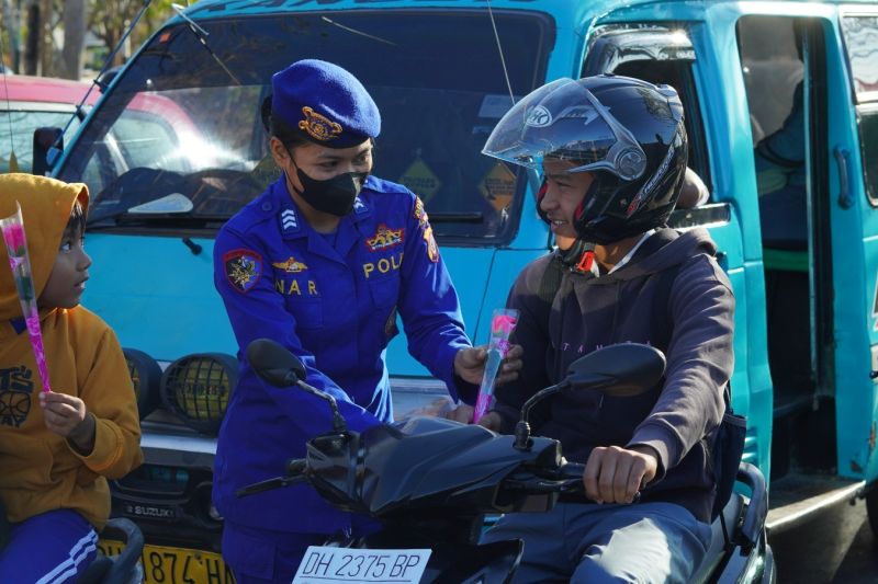 Seorang Polwan dari Polda NTT memberikan bunga kepada seorang pengendara bermotor di Kupang, Selasa. ANTARA/Ho-Humas Polda NTT