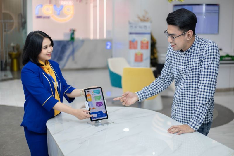 Ilustrasi - Petugas membantu nasabah menggunakan aplikasi Bank Raya. ANTARA/HO-Bank Raya.