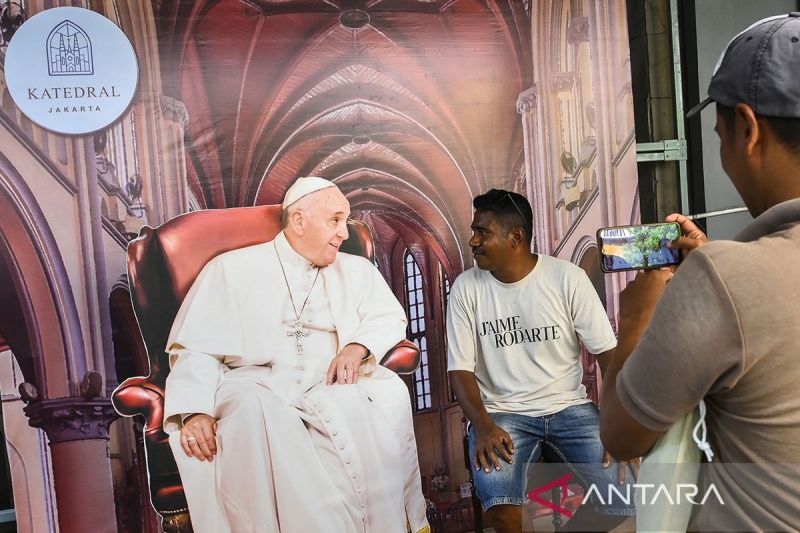 Warga berfoto dengan dekorasi bergambar Paus Fransiskus yang terpasang di Gereja Katedral Jakarta, Sabtu (31/8/2024). (ANTARA/Sulthony Hasanuddin)