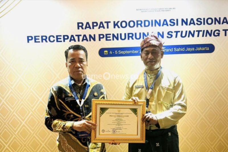 Penjabat Kepala Desa Mentayan, Honest Nazaldy didampingi Plt Kepala Dinas Pemberdayaan masyarakat Desa Bengkalis, Ismail ketika menerima penghargaan terbaik II penurunan stunting 2024.ANTARA/HO-Diskominfotik Bengkalis