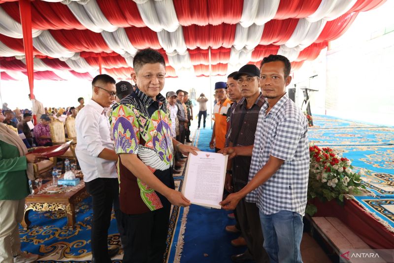 Bupati OKU Timur Lanosin Hamzah menyerahkan surat keputusan pengelolaan lahan OPLAH kepada kelompok tani di wilayahnya, Jumat. (ANTARA/HO/Diskominfo)