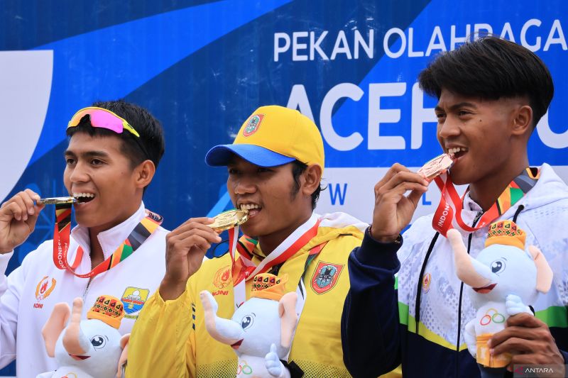 Para atlet dayung nomor kayak putra 200 meter menggigit medali usai memenangi pertandingan cabang olahraga tersebut pada PON XXI di Kabupaten Aceh Besar, Sabtu (7/9/2024). ANTARA/Muhammad Zulfikar.