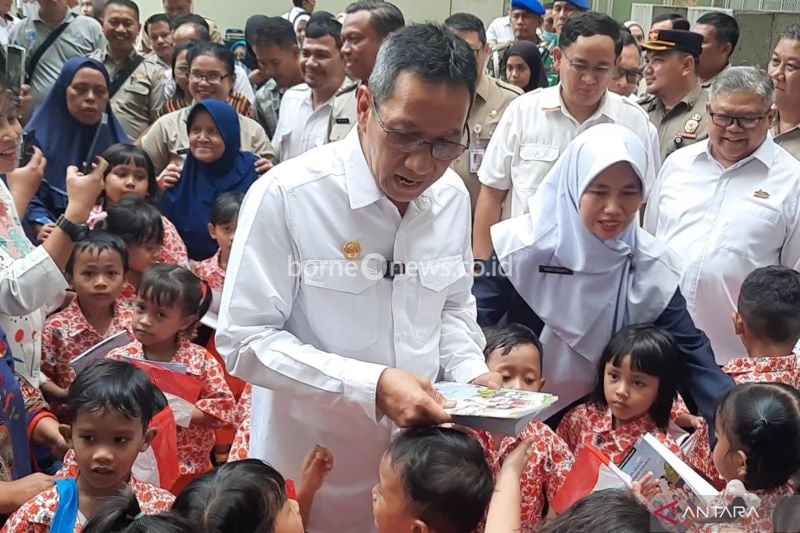 Penjabat Gubernur DKI Jakarta Heru Budi Hartono saat membagikan buku tulis kepada anak-anak penyintas kebakaran di kawasan Manggarai, Tebet, Jakarta Selatan, yang direlokasi ke Rumah Susun Pasar Rumput, Jakarta, Senin (9/9/2024). (ANTARA/Lia Wanadriani Santosa)