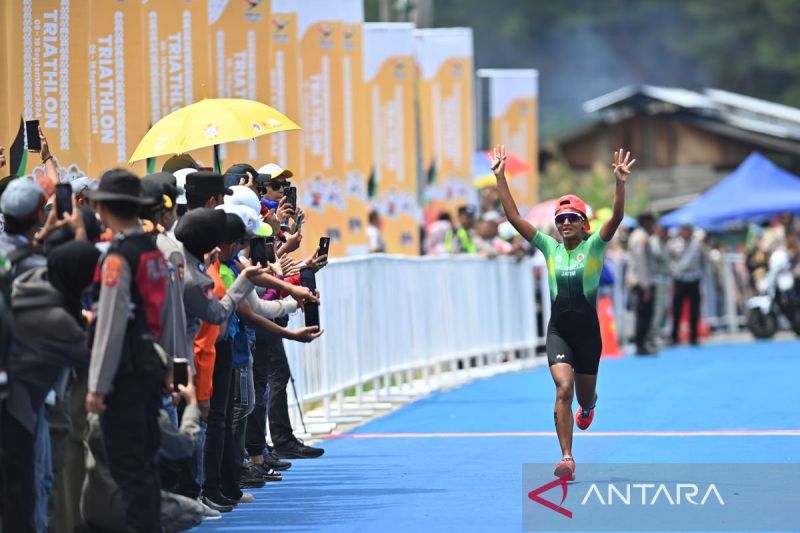 Atlet triathlon Jawa Timur Binta Erlen Salsabila mengangkat tangan usai finis pertama dalam perlombaan triathlon standar putri PON XXI Aceh-Sumut 2024 di Takengon, Kabupaten Aceh Tengah, Aceh, Rabu (11/9/2024). Binta Erlen Salsabila meraih medali emas setelah finis pertama dengan catatan waktu 2 jam 9 menit 17 detik sementara atlet Aceh Renata Berliana Aditya meraih perak dengan waktu 2 jam 10 menit 16 detik dan atlet Kalimantan Barat Maharani Azhri Wahyuningtyas raih perunggu dengan waktu 2 jam