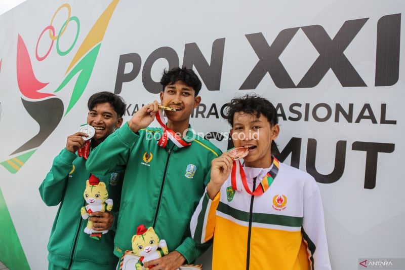 Pembalap sepeda Jawa Timur Muhammad Syelhan Nurrahmat (tengah) bersama Rizky Aditya Noufal (kiri), dan pembalap sepeda Kalimantan Timur Aditya Suryadi Putra (kanan) mengigit medalinya seusai upacara penghargaan pemenang nomor Individual Road Race Jarak Jauh PON XXI Aceh-Sumut 2024 di kawasan Danau Toba, Simalungun, Sumatera Utara, Kamis (12/9/2024). Pembalap sepeda putra Jawa Timur Muhammad Syelhan Nurrahmat berhasil meraih medali emas dengan catatan waktu 3 jam 9 menit 38 detik, disusul atlet J