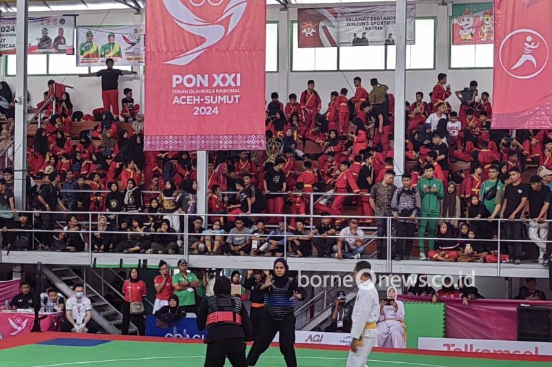 Pelajar dari SMP Muhammadiyah 1 Medan saat menyemangati para pesilat yang tengah bertanding dalam PON XXI Aceh-Sumatera Utara yang dihelat di GOR Veteran, Medan, Jumat (13/9/2024). (ANTARA/Asep Firmansyah)