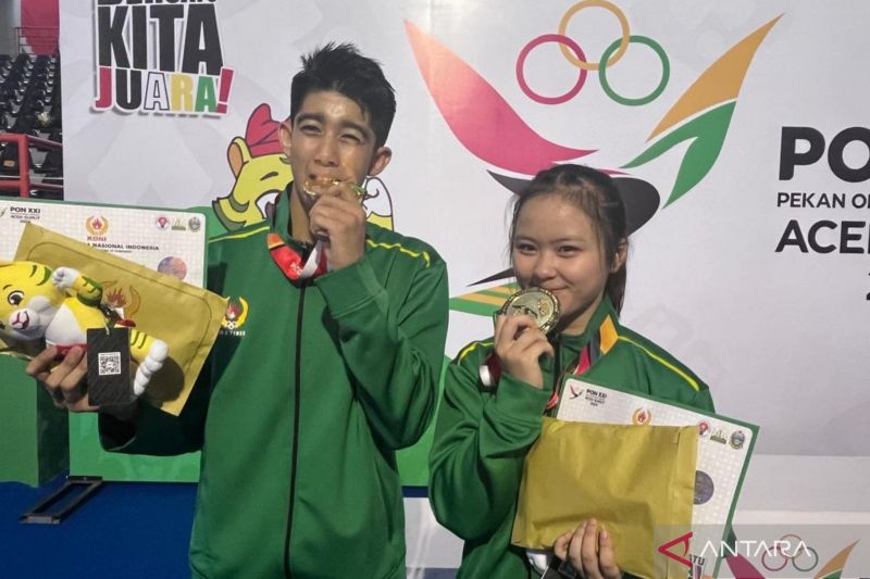 Atlet Jawa Timur Michael Arroll Nestor Jennings (kiri) dan Jessie Djalimin berfoto dengan medali emas yang mereka raih pada nomor taolu wing chun wooden dummy + wing chun butterfly sword putra dan putri cabang olahraga wushu di Pekan Olahraga Nasional (PON) Aceh-Sumut, di GOR Disporasu, Deli Serdang, Sumatera Utara, Jumat (13/9/2024). (ANTARA/Fathur Rochman)