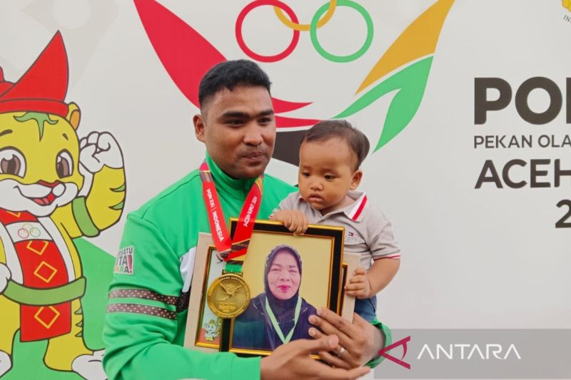 Hardodi Sihombing sambil membawa buah hatinya berpoto usai pengalungan medali (ANTARA/Juraidi)