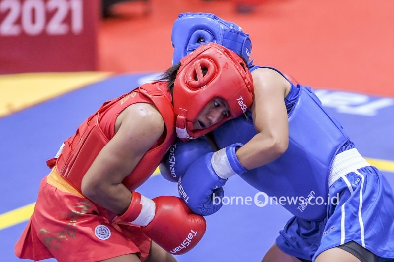 Atlet wushu putri Jatim Friska Ria Wibowo (kiri) berusaha memukul Atlet wushu putri Sumut Junita Malau (kanan) saat bertanding pada semifinal Wushu Sanda Putri nomor 48 Kg PON Papua di Gor Futsal Dispora, Kabupaten Merauke, Papua, Jumat (1/10/2021). ANTARA FOTO/Galih Pradipta/YU (ANTARA FOTO/GALIH PRADIPTA)
