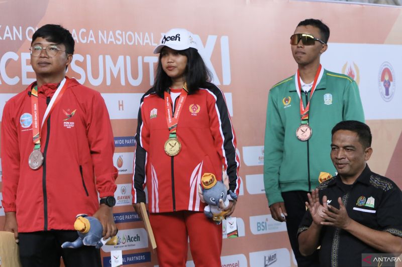 Atlet aeromodelling Aceh Fidela Avionic (tengah) usai menerima medali emas perdana pada nomor terbang bebas tarik A1 atau F1H dalam PON Aceh-Sumatera Utara 2024 di Lanud Maimun Saleh, Kota Sabang, Aceh, Sabtu (15/9/2024). (ANTARA/Khalis Surry)