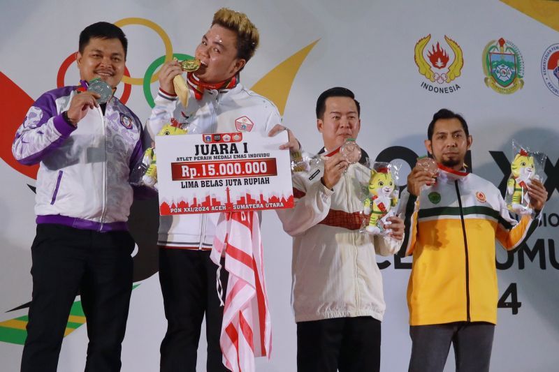 Pebiliar dari tim DKI Jakarta Edward (kedua kiri) berpose sambil menggigit medali emas yang diraih setelah memenangkan laga final nomor 15 ball single putra cabang biliar PON Aceh-Sumut 2023 di Pardede Hall, Medan, Senin (16/9/2024). (ANTARA/HO-PB PON Aceh-Sumut 2024/Raden Armand)