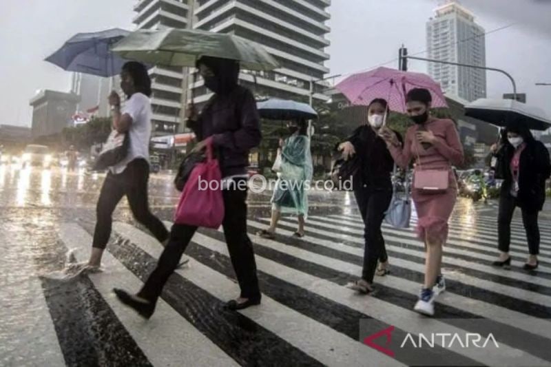 Ilustrasi - Sejumlah karyawati menyeberangi jalan yang tergenang air di depan gedung perkantoran saat hujan ringan. ANTARA/Muhammad Adimaja/am