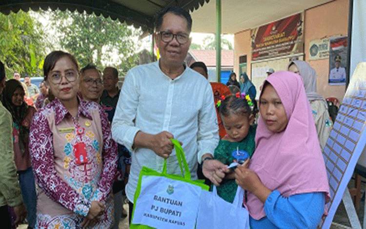 Pj Bupati Kapuas, H Darliansjah saat menyerahkan simbolis makan tambahan kepada sejumlah anak, bertempat di halaman Kantor Kelurahan Palingkau Baru, Kecamatan Kapuas Murung. (FOTO: IST)