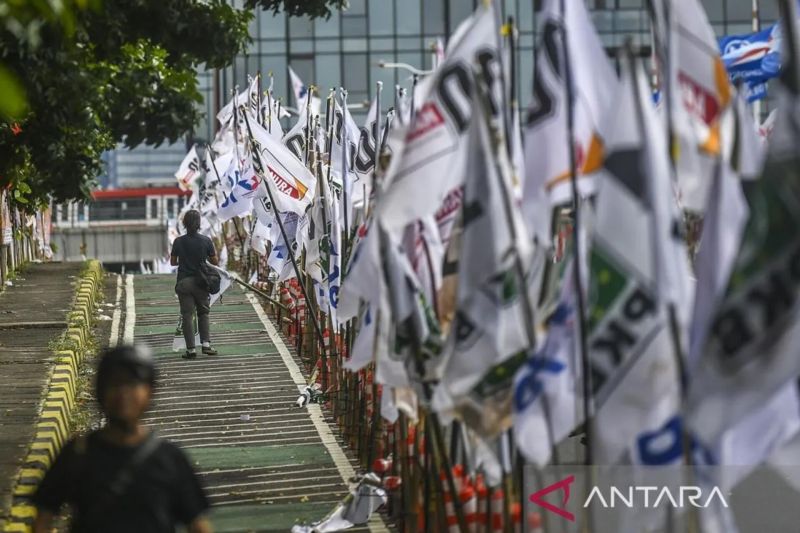 Warga melintas di samping alat peraga kampanye (APK) pemilu 2024 yang terpasang di pembatas jalur sepeda (stick cone) di Jakarta, Senin (8/1/2024). ANTARA FOTO/Galih Pradipta/pras.