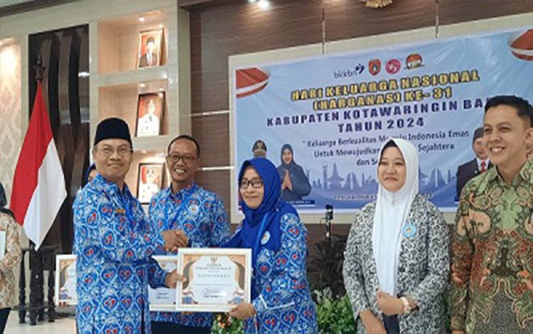 Kepala DP3AP2KB Kobar Agus Basra saat memberikan penghargaan kepada salah satu penerima, dalam kegiatan Harganas ke 31 Kobar. (Foto : DANANG)