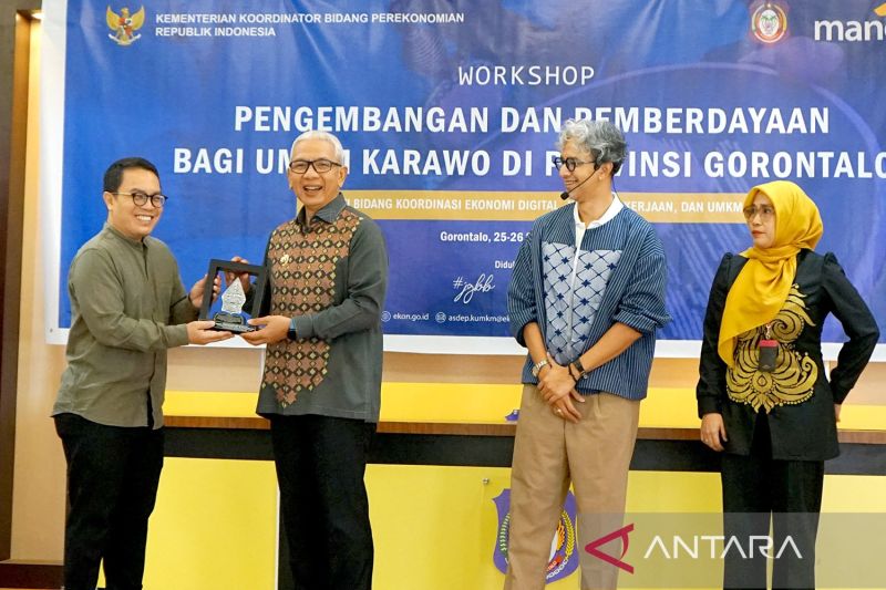 Asisten Deputi Koperasi dan UMKM, Kementerian Koordinator Bidang Perekonomian Herfan Brilianto Mursabdo (kiri) menyerahkan plakat kepada Pj Gubernur Gorontalo Rudy Salahuddin (kedua kiri) pada workshop pengembangan dan pemberdayaan di Kota Gorontalo, Gorontalo, Rabu (25/9/2024). ANTARA/Adiwinata Solihin