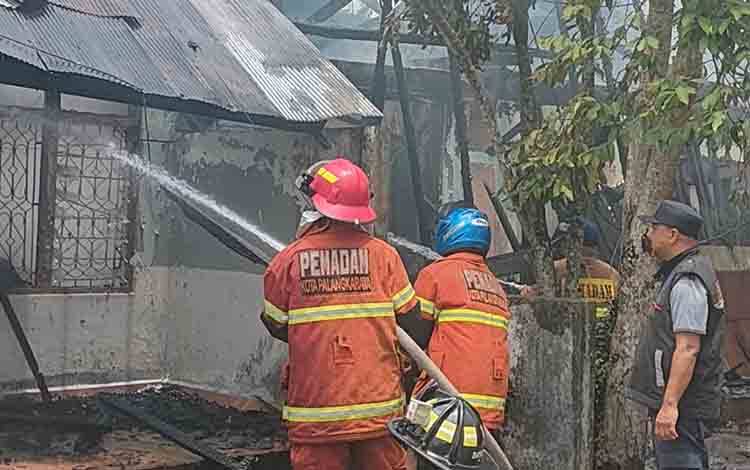 Tim gabungan pemadam kebakaran saat melakukan upaya pendinginan rumah dinas Telkom yang terbakar. (FOTO: PATHUR)