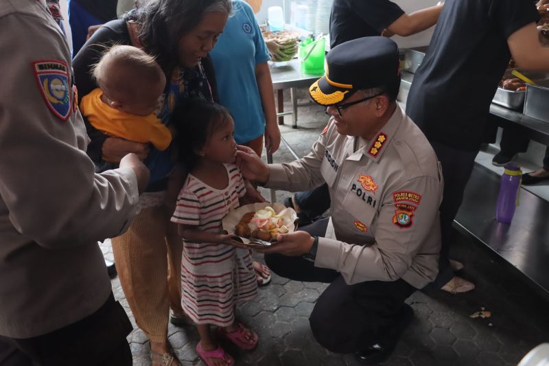 Kapolres Metro Jakarta Utara Kombes Pol Gidion Arif Setyawan membawakan makanan untuk seorang anak di kawasan Pluit, Jakarta Utara, dalam program "Jumat Berkat", pada Jumat (4/10/2024). ANTARA/HO-Polres Jakut