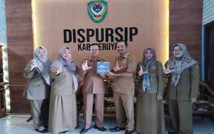 Kadis Perpustakaan dan Kearsipan Seruyan, Mulyadie menerima penyerahan buku dari Lurah Kuala Pembuang I, Menteng Delpris yang merupakan hasil karyanya (Foto : Ist)