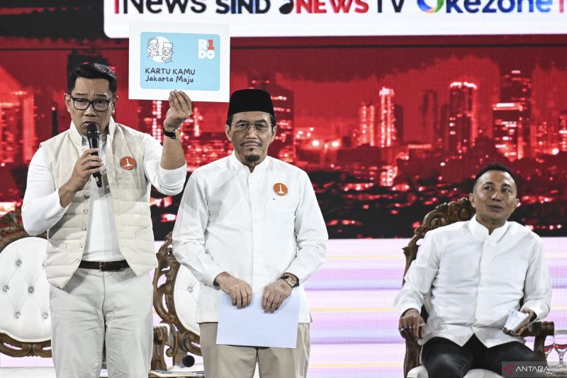 Pasangan calon Gubernur-Wakil Gubernur DKI Jakarta nomor urut satu Ridwan Kamil (kiri) dan Suswono (kedua kiri) disaksikan Cagub DKI Jakarta nomor urut dua Dharma Pongrekun (kanan) menunjukkan mock up Kartu Kamu Jakarta Maju pada debat pertama pasangan Calon Gubernur dan Wakil Gubernur DKI Jakarta tahun 2024 di JIExpo Kemayoran, Jakarta, Minggu (6/10/2024). Debat perdana tersebut mengangkat tema penguatan SDM dan transformasi Jakarta menjadi Kota Global. ANTARA FOTO/Aprillio Akbar/aww.