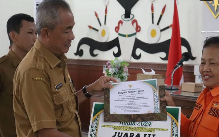 Pj Sekda Palangka Raya, Arbert Tombak saat menyerahkan hadiah lomba inovasi daerah. (FOTO: HENDRI)?