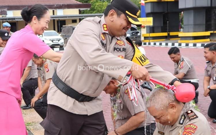 Kapolres Seruyan AKBP Hans Itta P!?didampingi Ketua Bhayangkari Cabang Seruyan Ny. Kristy Hans melakukan siraman kepada personel yang menerima kenaikan pangkat (Foto ; Ist)