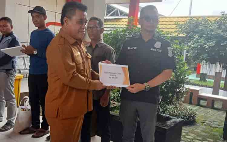 Plt Kepala DP3AP2KB Bakhzar Efendi saat menyerahkan penganti biaya tidak bekerja kepada salah satu aseptor vasektomi, Senin 21 April 2025. (FOTO: RETHA)