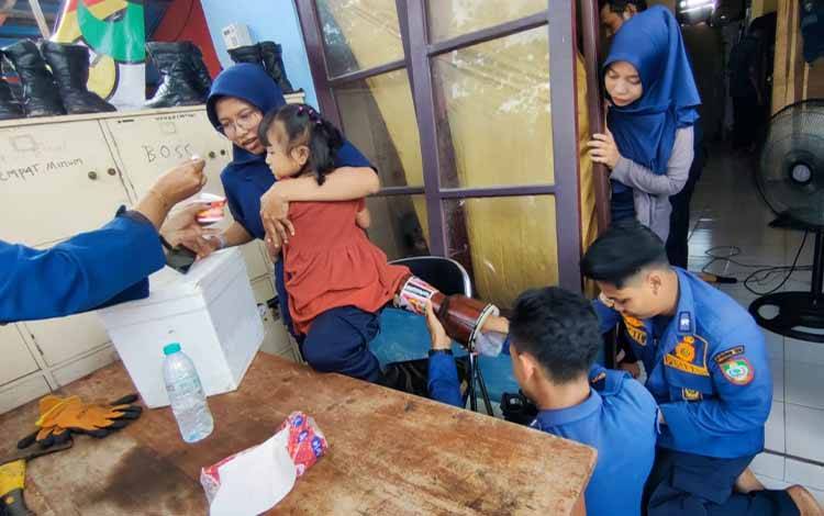 Petugas Disdamkarmat Kotawaringin Timur berusaha melepaskan gendang dari kaki seorang balita, Kamis, 24 April 2025. (FOTO: IST)