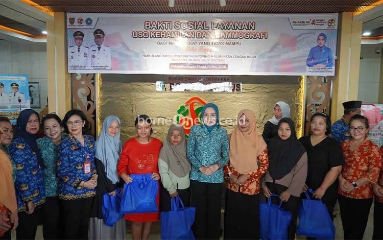 Ketua TP-PKK Kalteng Aisyah Thisia Agustiar Sabran foto bersama saat penyerahan bingkisan kepada peserta Bakti Sosial. (FOTO: IKHSAN)